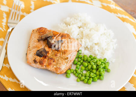 Crispy grilled salmon fillet with roasted portobello mushrooms and sweet glaze with peas and rice on the side Stock Photo