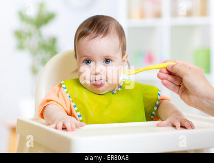 happy baby child sitting in chair with a spoon Stock Photo