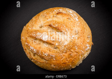 Whole Sesame Roll on Black Slate Board Isolated on a White Background Stock Photo