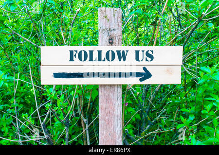 FOLLOW US written on Directional wooden sign with arrow pointing to the right against green leaves background. Concept image with available copy space Stock Photo