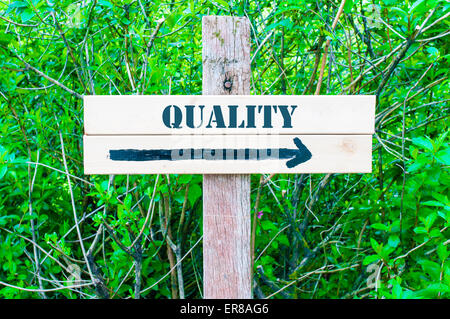 QUALITY written on Directional wooden sign with arrow pointing to the right against green leaves background. Concept image with available copy space Stock Photo