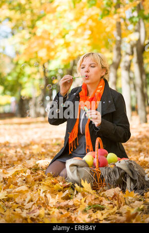 pregnant woman blow bubbles in autumn park Stock Photo