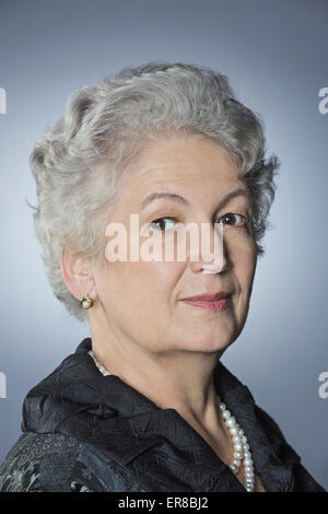 Portrait of confident senior woman over gray background