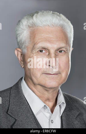 Close-up portrait of confident senior man over gray background Stock Photo