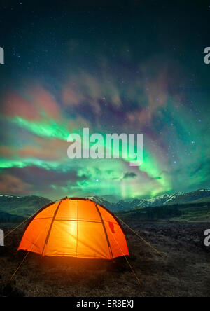 A camping tent glowing under the Northern Lights. Night time camping scene. Stock Photo