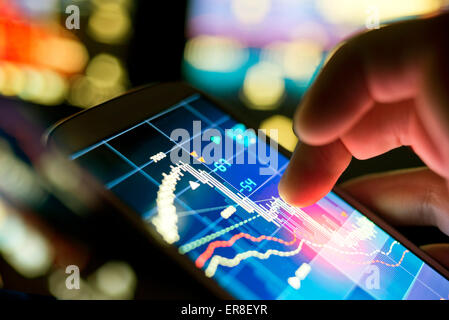 A businessman using a mobile phone to check stock market data. Stock Photo