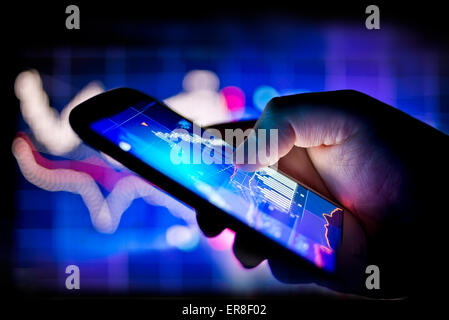 A person using a mobile phone to track real time stocks and shares data Stock Photo