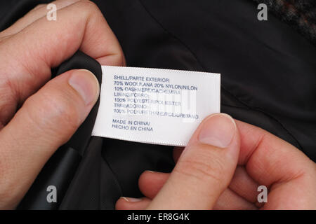 Woman's hands holding clothes label with fabric information. Made in China. Stock Photo