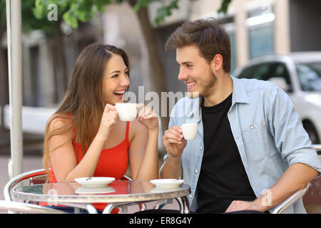 Happy couple or friends flirting talking and drinking in a restaurant terrace Stock Photo