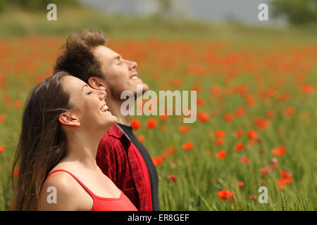 Happy couple breathing fresh air in a colorful field with red poppy flowers Stock Photo