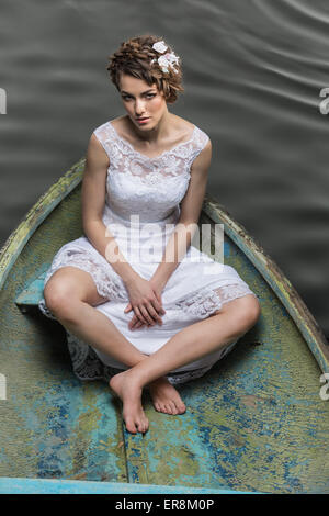 High angle portrait of sad young bride sitting in boat on lake