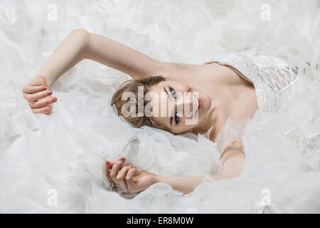 Portrait of smiling young bride in wedding dress lying down Stock Photo