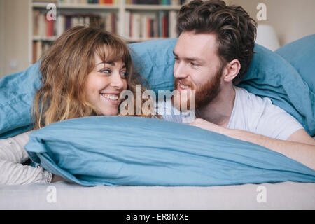 Loving young couple looking at each other while lying in bed Stock Photo