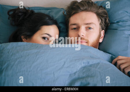 Portrait of loving young couple under duvet in bed Stock Photo