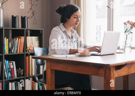 Young woman using laptop at table Stock Photo