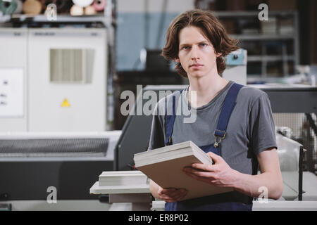 Portrait of confident manual worker holding cardboard sheets in factory Stock Photo