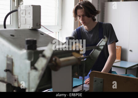 Young manual worker operating machine in factory Stock Photo