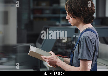 Side view of young manual worker examining cardboard sheets in factory Stock Photo