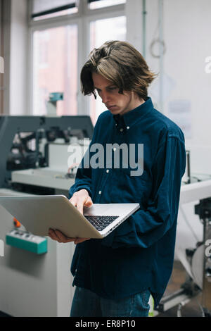 Young male technician using laptop in factory Stock Photo