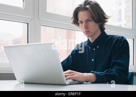 Confident young man using laptop at a desk Stock Photo