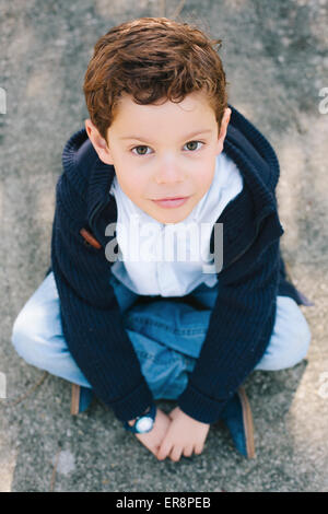 High angle portrait of boy sitting on street Stock Photo