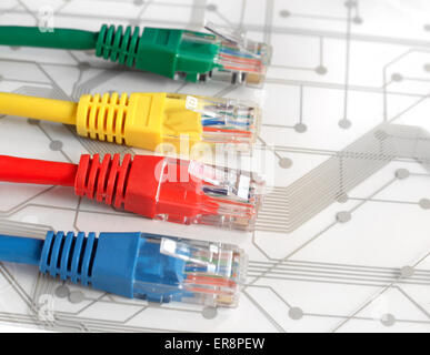 Four Multi Colored Network Cables. Red, Yellow, Green, Blue Color. Cables are lying on top of White Circuit Board Stock Photo