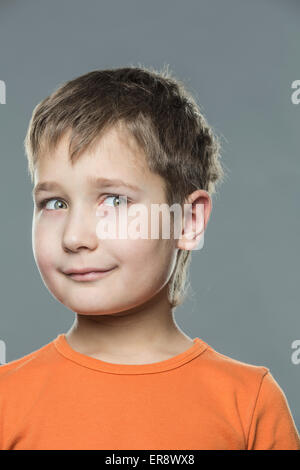Thoughtful boy looking away against gray background Stock Photo