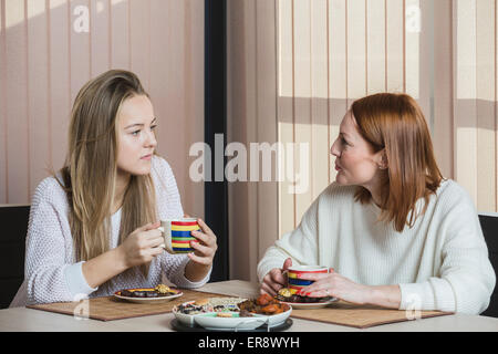 Mother and daughter talking while having breakfast at home Stock Photo