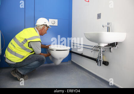 A plumber installs a toilet bowl in a new London school Stock Photo