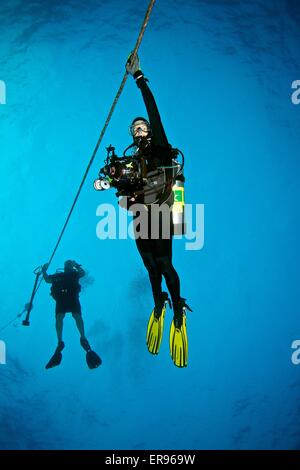 SCUBA divers hang on the down line doing their safety stop after a deep dive Stock Photo