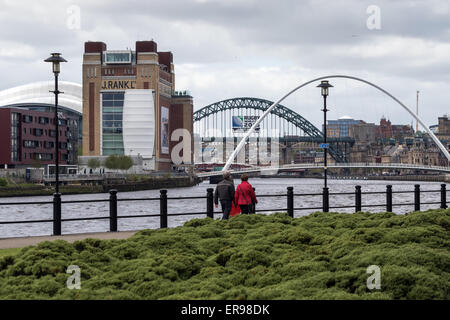 A couple walk along the banks of the Tyne in Newcastle, with the Baltic and Sage, Gateshead, on the left Stock Photo