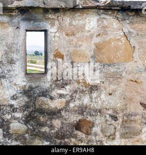 Stone wall little window. Behind the wall another world Stock Photo