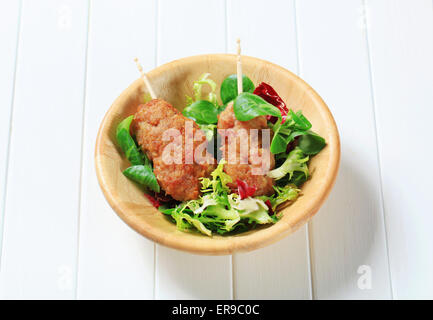 Rolled minced meat on stick served with green salad Stock Photo