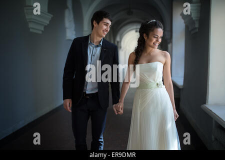 Happy couple playfully goes down a long corridor Stock Photo