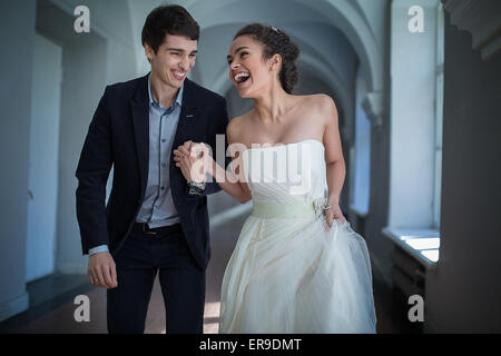 Happy couple playfully goes down a long corridor Stock Photo