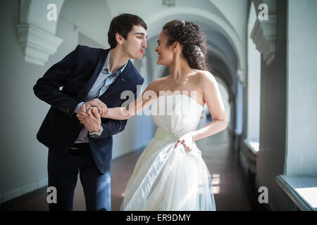 Happy couple playfully goes down a long corridor Stock Photo