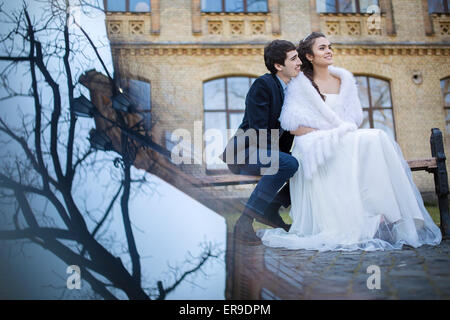 Wedding couple embracing sitting on a park bench Stock Photo