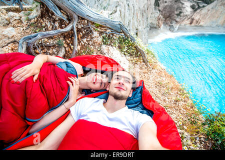 Young couple in sleeping bags near the sea Stock Photo