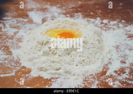 Making bread, mixing food ingredients: egg yolk on a flour staple closeup. Retro colors Stock Photo