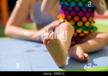 Mother holding her little daughter feet wearing colorful swimsuits on the table closeup Stock Photo