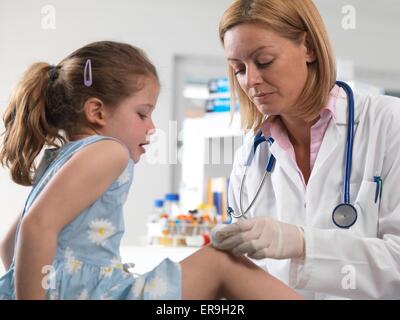 PROPERTY RELEASED. MODEL RELEASED. Doctor cleaning a knee wound in a accident clinic. Stock Photo