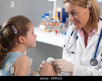 PROPERTY RELEASED. MODEL RELEASED. Doctor cleaning a knee wound in a accident clinic. Stock Photo