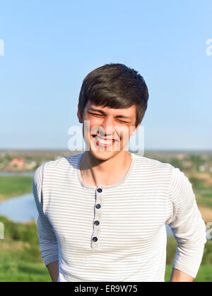Summer portrait of a handsome young man laughing. Soft evening sunlight Stock Photo
