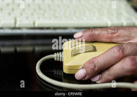 Female hand using retro computer mouse, keyboard in the blurred background Stock Photo