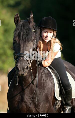 girl rides Friesian horse Stock Photo