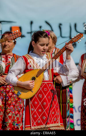 A young female Bulgarian folklore musician playing bouzouki during the traditional folklore festival '1000 national costumes' Stock Photo