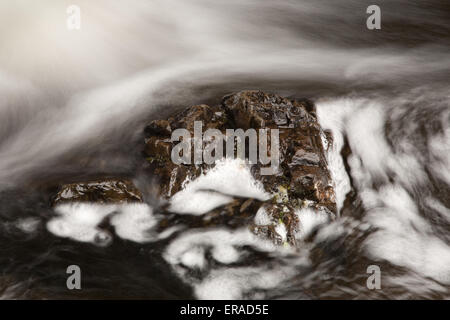 Brown rock with turbulent water flow. Long exposure effect. Stock Photo