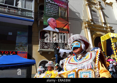 La Paz, Bolivia, 30th May 2015. A kullaguada dancer passes a banner of Pope Francis hanging outside the Sanctuary of El Señor del Gran Poder during parades for the Gran Poder festival. Pope Francis will visit La Paz during his 3 day trip to Bolivia planned for July 2015. The festival in honour of El Señor del Gran Poder takes place today and is the biggest festival in La Paz. Stock Photo