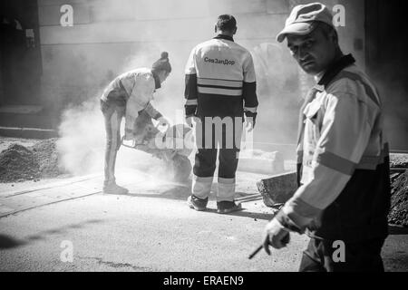 Saint-Petersburg, Russia - May 23, 2015: men at work, urban road under construction, sawing of roadside border stones, black and Stock Photo