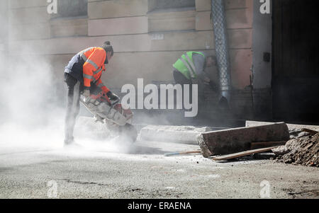 Saint-Petersburg, Russia - May 23, 2015: men at work, urban road under construction, sawing of roadside border stones Stock Photo